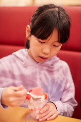 外食の店でパフェアイスクリームを食べる小学生の女の子の姿