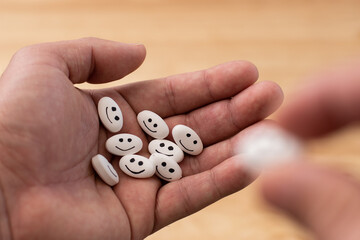 Hand holding a pill with a happy face in the medicine pill with close up and bokeh background