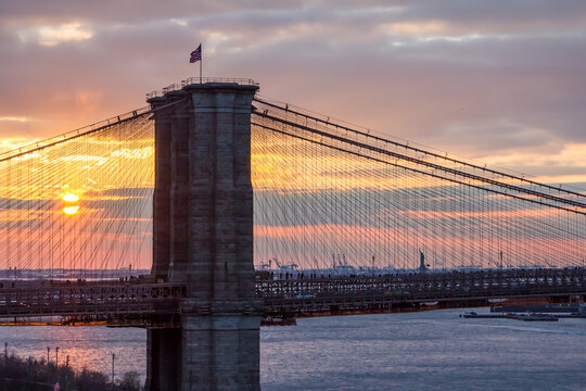 The setting sun paints a colorful sky behind the Brooklyn Bridge in New York City NYC