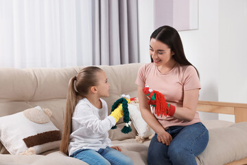 Happy mother and daughter playing with funny sock puppets together at home
