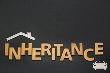 Word Inheritance made with wooden letters and different cutouts on black background, flat lay. Space for text