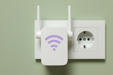 New modern repeater with Wi-Fi symbol plugged into socket on light green wall