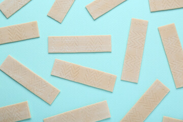 Many sticks of tasty chewing gum on light blue background, flat lay