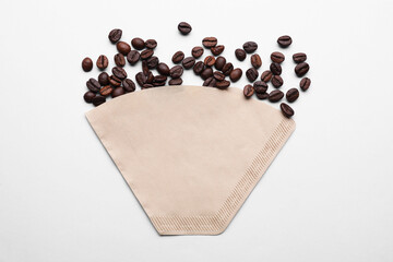 Paper coffee filter and beans on light grey background, flat lay