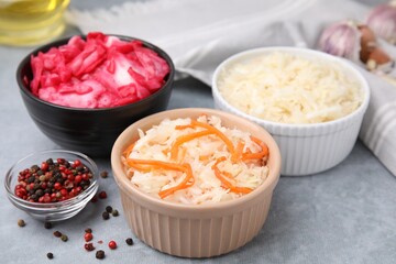 Delicious sauerkraut prepared according to different recipes and spices on light gray table, closeup