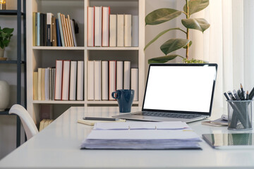 White working desk with laptop computer, accountant documents, coffee cup and office supplies.