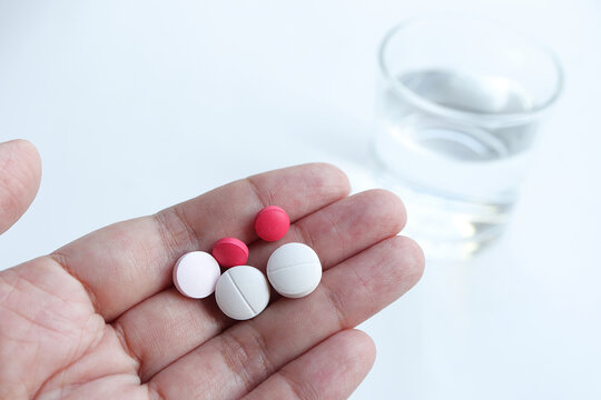 Close Up Of Hand Woman Holding Taking Multiple Pills On Blur Water Glass Background. Medicine, Healthcare Concept.