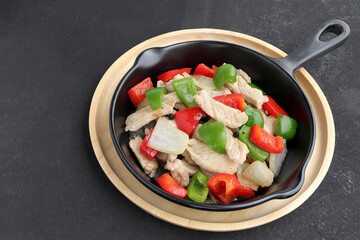 Delicious Stir fried pork with sweet peppers, onion and black pepper on black pan. Top view.