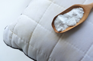 White pillow with yellow saliva stains and baking soda (sodium bicarbonate) on white background. baking soda to clean their dirty mattresses and Home cleaning concept.