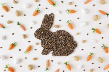 Trendy composition with easter bunny  shape made of coffee roasted beans,Easter eggs in pastel colors and carrot.Creative Realistic art, minimal  aesthetic look. Contemporary style.Top view.Flat lay