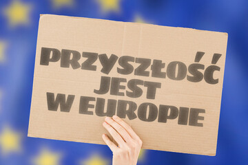 The phrase " The future is Europe " is on a banner in men's hands with a blurred European Union flag in the background. EU. Politics. Community. Unity. Society. Partnership. Strong. Powerful. Economy