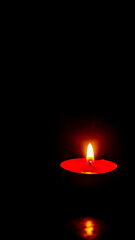 a burning candle against a dark background