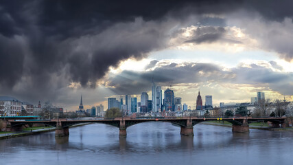 Fototapeta premium Panorama shot of cloudburst and sun rays shining on Frankfurt Skyline and Banking District