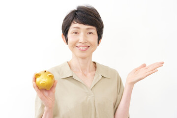 貯金箱を持って手のひらで右を指す中年女性　白背景