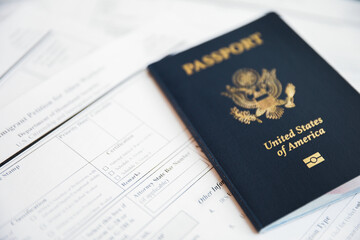 Close-up of a US passport with immigration, visa, citizenship, and travel paperwork on a wooden table