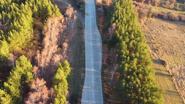 Golden hour aerial centered shot of a car moving on a mountain road surrounded by trees. Shot on the I-6 Sub Balkan road in Bulgaria