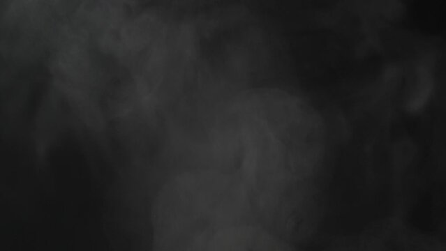White steam spins and rises from cooking frying pan. White smoke rising from pot. Isolated black background. Slow motion. Full hd