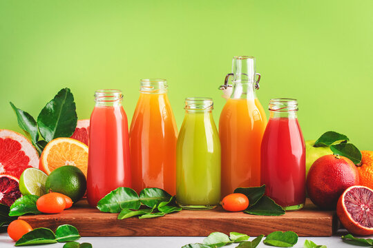 Summer drinks. Citrus fruit juices, fresh and smoothies, food background. Mix of different whole and cut fruits: orange, grapefruit, lime, tangerine with leaves and bottles with beverages