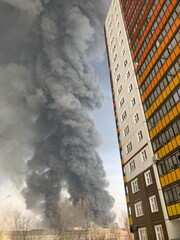 Large fire with black smoke. Burning industrial building, warehouse. A pillar of black smoke in the sky.