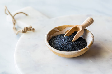 Black Hawaiian salt in a bowl with a small wooden scoop.