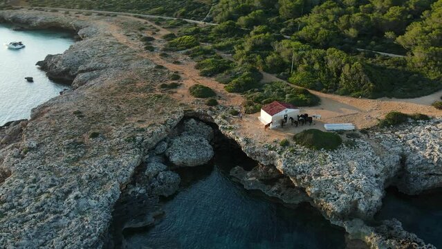 Small boat shed at the edge of a cliff in Sin Titulo with sun setting and shadows being cast. Aerial drone view panning around property