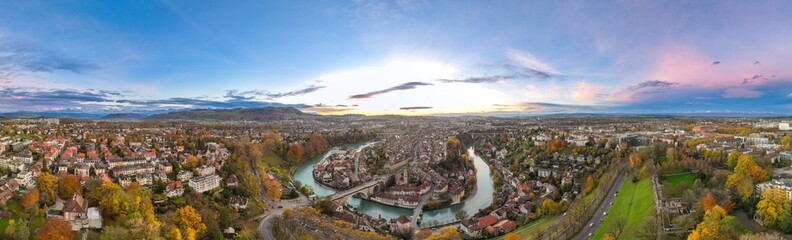 Wide establishing aerial sunset over Bern town, the capital city of Switzerland with colorful twilight romantic sky. Panorama view over Aare river Swiss historic cityscape traveling landmark in autumn - obrazy, fototapety, plakaty