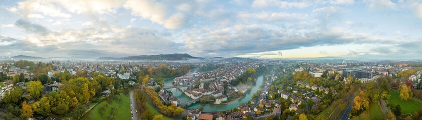 Aerial sunrise over Bern old town, the capital city of Switzerland with magical morning clouds and fog. Drone fly over Aare river Swiss historic cityscape landmark in autumn. Europe traveling concept. - obrazy, fototapety, plakaty