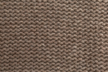 Knitted fabric in natural color. Hobby and needlework. Garter knitting. Close-up. Space for text.
