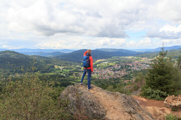 Fototapeta na wymiar Male hiker (man) standing on mountain Silberberg and looking at panorama of municipality Bodenmais in Bavarian Forest, Germany