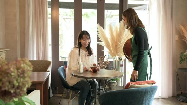 女性客の接客をするカフェの女性店員