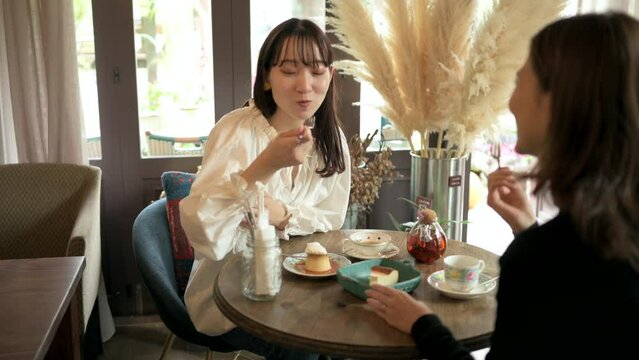 友人とカフェでデザートを食べる女性客