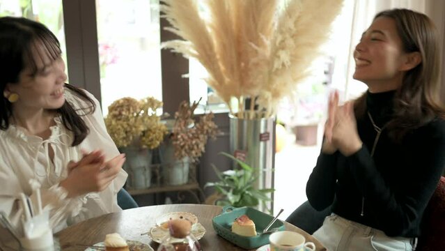 友達とカフェで談笑する若い女性客