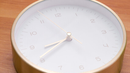 Close-up shot of a blue dial golden clock lying on a wooden table.