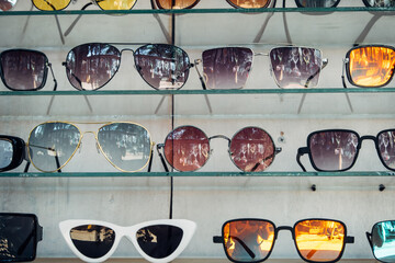 A showcase with a large number of fashionable sunglasses of different shapes. Background for...