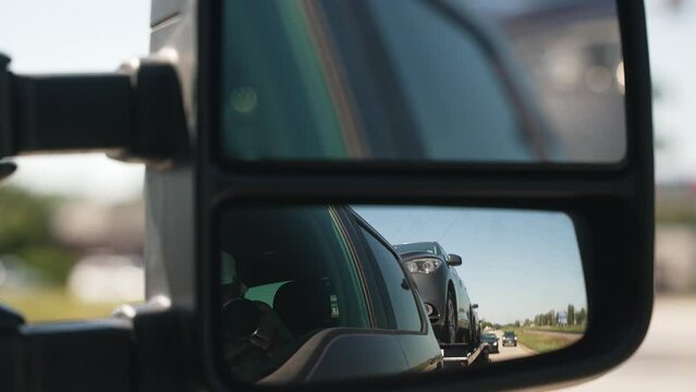 unique view of a cars hauled by a wedge car trailers-carhauling as making a turn. With small reflection in the window. Trailer is pulled by a pickup truck. Similar view as tow truck