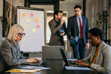Colleagues celebrating a birthday in the office. Two businessmen give a present to their female coworkers.
