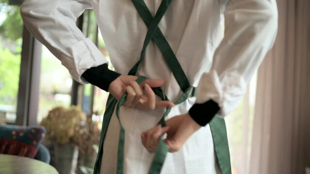 エプロンの紐を結ぶ女性