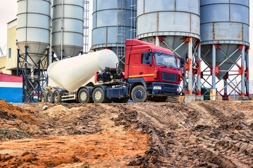 Large truck for transporting cement. A cement truck unloads cement at a concrete plant. Concrete...