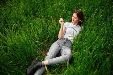 woman in gray jeans resting lying in the grass