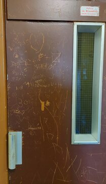 verkratzte Tür eines alten Aufzugs mit Grrafiti 