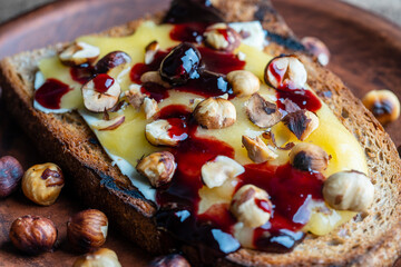 Bread toast with butter, roasted hazelnuts, honey, berry jam on plate , closeup