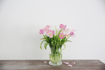 Bouquet of pink tulips in vase on wooden table. Still life floral arrangement 