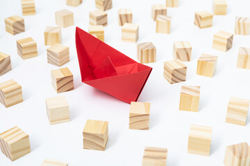Conceptual photo of a paper ship and wooden blocks to overcome a business crisis