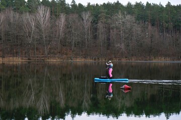 A woman is paddling on a SUP board on lake Borowno Wielkie, Kociewie, Pomerania, Poland