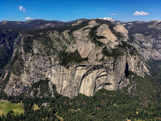 Massive rock mountains with cliffs, waterfalls cascades river creeks, meadows flowers and woods in...
