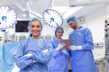 Portrait of female woman nurse surgeon OR staff member dressed in surgical scrubs gown mask and hair net in hospital operating room theater making eye contact smiling pleased happy looking at camera - obrazy, fototapety, plakaty