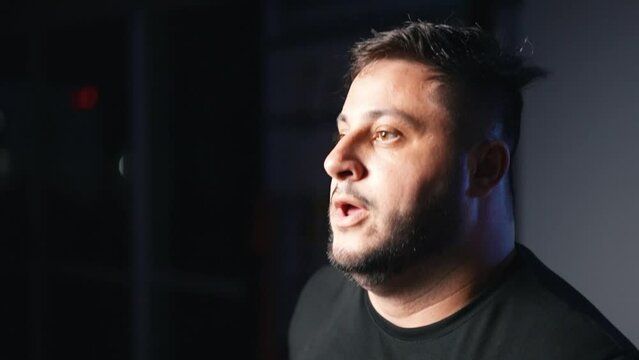 Dynamic shot energetic overweight man running in place as a cardio exercise in a dark gym training hard in slow motion