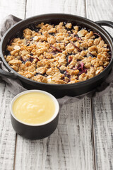 Swedish pie Smulpaj baked with apples and blueberries close-up in a pan on the table. Vertical