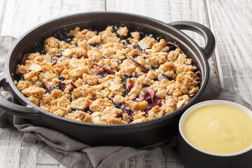 Berry fruit crumble baked with apples and blueberries served with vanilla sauce close-up in a pan on the table. Horizontal