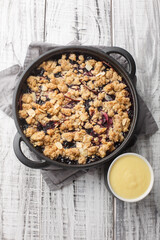 Swedish Fruit Crumble Pie Smulpaj with home made vanilla sauce closeup on the wooden table. Vertical top view from above